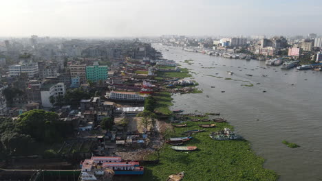 Aerial:-ship-wrecking-dockyard-at-Buriganga-river-bank-with-cityscape---drone-flying-forward-shot