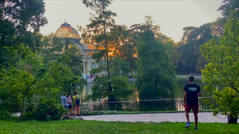 Man-taking-pictures-of-the-Crystal-Palace-or-palacio-de-cristal-in-Retiro´s-park-at-sunset-in-Madrid-city
