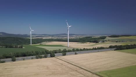 Luftumlaufbahn-Von-Windmühlenturbinen-Auf-Landwirtschaftlichen-Feldern-Tagsüber,-Die-Saubere-Erneuerbare-Energie-Für-Eine-Nachhaltige-Entwicklung-Erzeugen