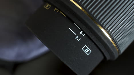 A-close-up-shot-of-a-fixed-aperture-DSLR-camera-lens,-the-focus-ring-rotating-as-it-retracts-the-core-of-the-lens-which-is-marked-with-a-distance-scale-and-used-as-an-aid-to-focus-the-subject