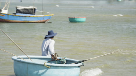 Vietnamesischer-Fischer-Trägt-Ein-Rundes-Fischerkorbboot-Zurück-Zum-Strand