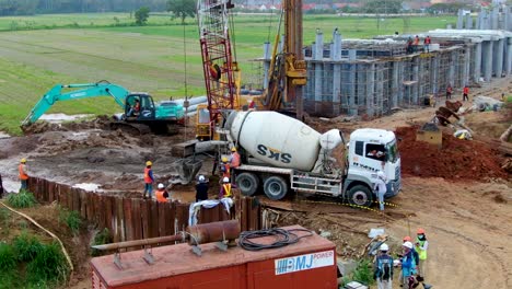 Excavators-and-cement-machine-working-on-monorail-project-in-Kulon-Progo,-aerial-view