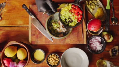 Zubereitung-Von-Ceviche-Salat-–-Blick-Von-Der-Tischplatte-Nach-Unten-Auf-Einen-Koch,-Der-Grüne-Paprika-In-Brunoise-Würfel-In-Eine-Schüssel-Mit-Geschnittenen-Meeresfrüchtezutaten-Schöpft-–-Kochszenenkonzept