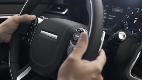 man-using-steering-wheel-buttons-of-rane-rover-velar,-modern-land-rover-,-luxury-car-steering-wheel