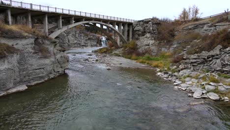 Slow-motion-aerial-shot-approaching-an-old-arch-bridge-near-Lundbreck-falls-in-southern-Alberta,-Canada