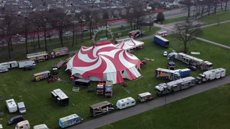 Planet-circus-daredevil-entertainment-colourful-swirl-tent-and-caravan-trailer-ring-aerial-wide-shot-zooming-in-view