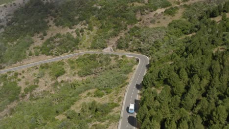 Aerial-shot-of-beautiful-VW-Camper-van-driving-down-a-scenic-mountain-road-in-Madeira