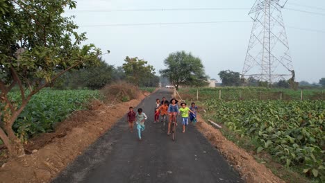 Indian-child-on-bicycle-running-aerial-view,-village-aera-road,-vintage-look,-indian-village-life-aerial-2