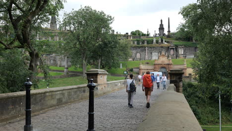 The-Bridge-of-Sighs-in-front-of-the-Glasgow-Necropolis,-Scotland-with-tourists-walking-around
