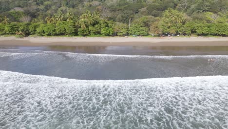 Aerial-view-of-waves-crashing-the-shoe-in-Dominical-Beach-in-Costa-Rica,-Tracking
