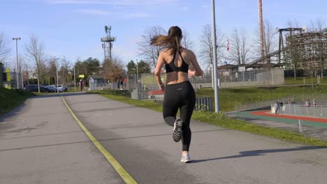 Athletic-woman-out-running-along-track-real-time-tracking-shot