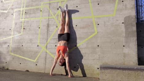 Woman-getting-into-handstand-position-against-wall-and-coming-down