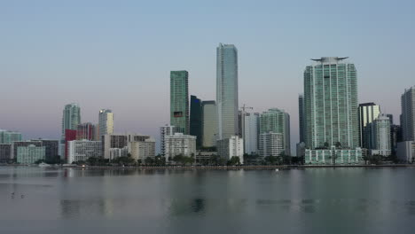 Vista-Aérea-Ascendente-Hacia-Rascacielos-Escénicos-En-El-Horizonte-Del-Paisaje-De-La-Ciudad-Frente-Al-Mar-De-Miami