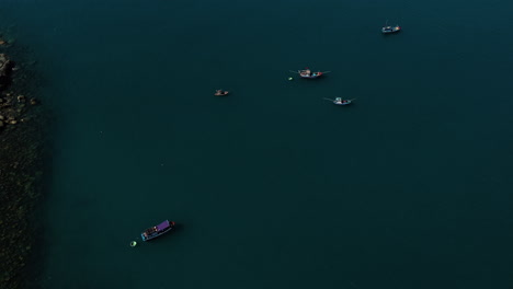 Small-fishing-boats-moored-near-massive-Ca-Na-port-under-construction-in-Vietnam,-aerial-view