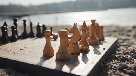 Antique-chessboard-on-sand-beach-by-the-water,-slow-motion-artistic-shot
