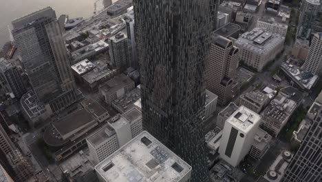 Drone-shot-tilting-down-at-Rainier-Square-Tower-amidst-Seattle's-downtown-skyscrapers