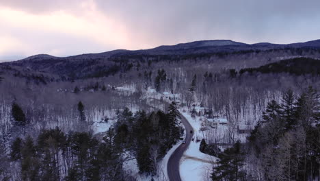 Cars-cross-paths-on-small-road-in-snowy-mountains-of-Vermont-during-sunset