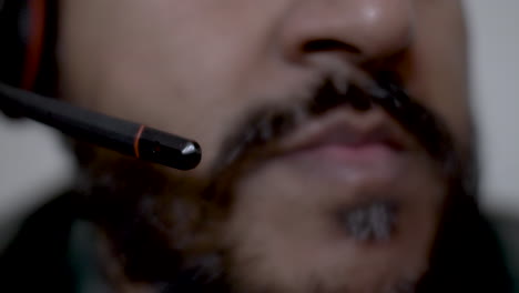 Close-Up-Shot-Of-Boom-Mic-Of-Headset-Coming-Down-With-Blurred-Background-Of-Ethnic-Minority-Bearded-Male-Talking