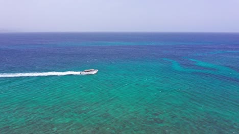 Aerial-tracking-shot-of-tourist-boat-cruising-over-tropical-Caribbean-Sea-during-summer