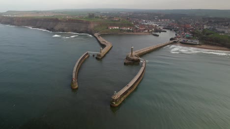 Aerial-Panorama-Of-Whitby-Harbour-East-Lighthouse-And-West-Pier-In-North-Yorkshire,-England,-UK