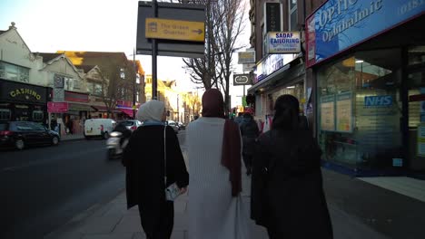 POV-Walking-Behind-Muslim-Females-Wearing-Hijabs-Along-Southall-High-Street-In-London