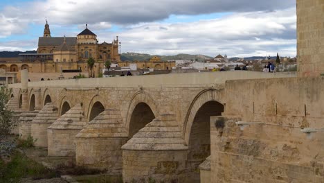 Calm-scenery-at-famous-Roman-Bridge-in-Cordoba,-Spain-with-Mezquita-in-back