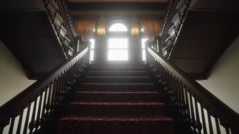 Old-Grand-Staircase-in-a-1900's-Mansion-with-Sun-Peaking-Through-Windows