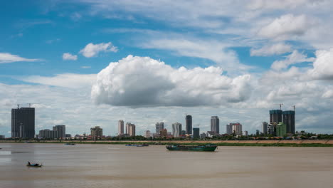 Phnom-Penh,-Eine-Sich-Verändernde-Skyline-Der-Stadt,-Die-Sich-Mit-Chinesischen-Hochhäusern-Füllt,-Während-Der-Fluss-Fließt-Und-Monsunwolken-über-Baustellen-Fegen