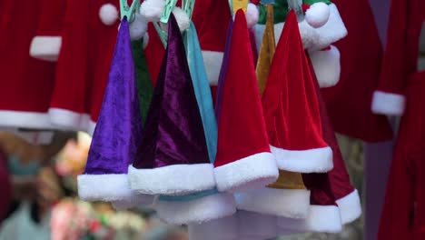 An-Einem-Straßenstand-In-Hongkong-Sind-Rote,-Violette-Und-Türkisfarbene-Weihnachtsmützen-Zum-Verkauf-Zu-Sehen