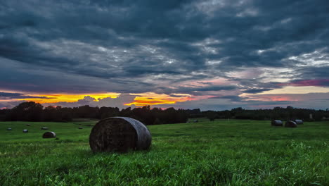 Moody-clouds-over-green-farm-landscape-time-lapse-with-round-hay-bales