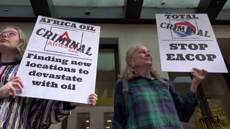 Two-climate-change-protestors-hold-placards-calling-Africa-Oil-and-Total-energy-companies-“criminal”-outside-the-Mayfair-Hotel-during-the-Africa-Energies-Summit