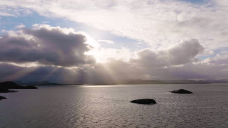 Crepuscular-rays--shine-through-clouds-over-coastline;-aerial