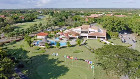 Vista-Aérea-Del-Hotel-Club-De-Campo-Metropolitano-Con-Piscina-Al-Aire-Libre-Junto-Al-Campo-De-Golf-Y-Fila-De-Banderas-Internacionales
