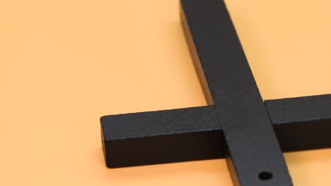 Wooden-christian-cross-over-orange-surface,-close-up-view