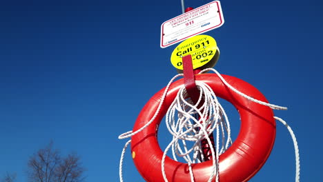 Medium-shot-looking-up-at-a-red-life-preserver-set-against-the-blue-sky