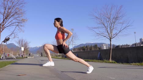 Athletic-young-woman-stretching-legs-on-curb