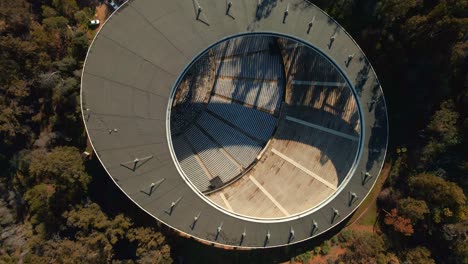 Aerial-top-down-spinning-over-Quinta-Vergara-Amphitheater-surrunded-by-tree-forest-in-park,-Viña-del-Mar-hillside,-Chile