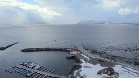 Ariel-Umlaufaufnahme-Des-Hafens-Von-Ase-In-Norwegen-Mit-Atemberaubendem-Blick-Auf-Schneebedeckte-Berge-Und-Den-Hafen-Mit-Booten