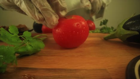 Cinematic-close-up-shot-of-chef-slicing-fresh-raw-tomato-on-chopping-board-in-kitchen