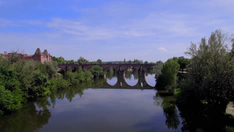 The-Old-Bridge-of-Montauban-France-crossing-the-Tarn-River-with-car-traffic,-Aerial-approach-shot