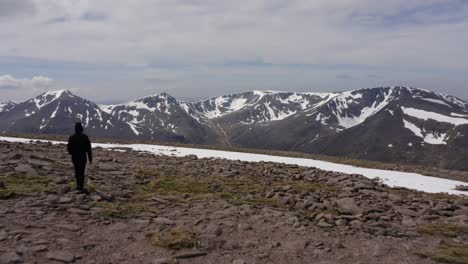 Montañas-De-Escocia-Cubiertas-De-Nieve-Con-Una-Persona-Que-Camina-Disparada-Por-Un-Dron