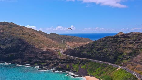 Aerial-view-of-paraglider-sailing-above-the-rocky-coastline-of-Makapuu