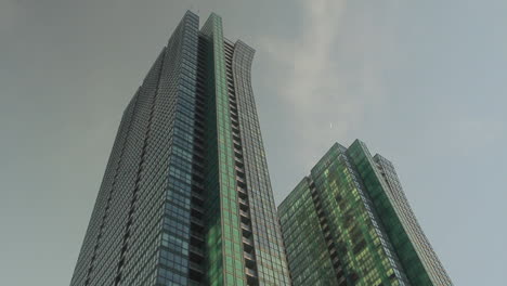 Looking-up-at-2-fun-colored-tall-buildings-in-front-of-a-grayish-sky-in-the-late-afternoon