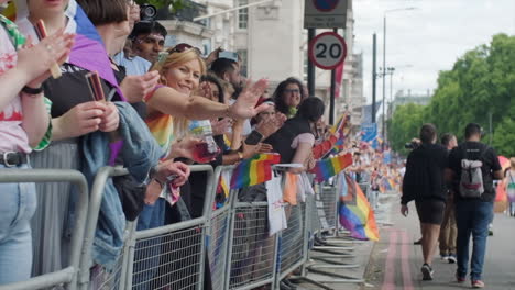 Slow-motion-shot-moving-past-Pride-march-spectators-waving-rainbow-flags