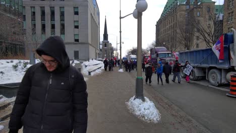 Large-crowds-of-Canadian-demonstrators-walking-along-parked-trucks,-protesting-Corona-Virus-Mandates