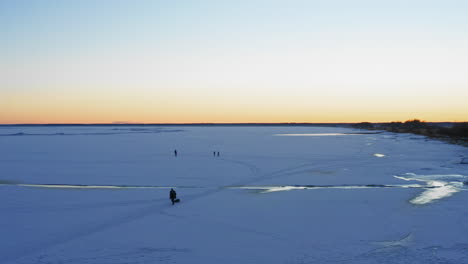 Person-drags-sled-through-snow-during-sunrise,-aerial-view