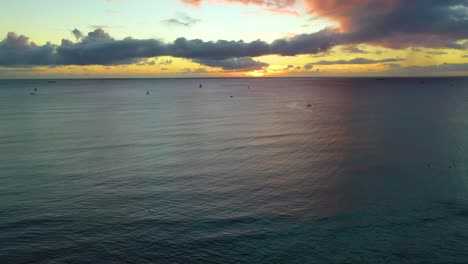 Drone-Flying-Over-A-Fleet-of-Sailboats-in-a-Hawaiian-Sunrise-Sailing-Across-The-Ocean-Waves-Off-the-Coast-of-Waikiki-Beach-In-Honolulu---Aerial-View