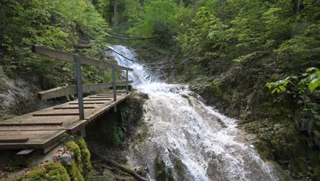 Slow-motion-shot-of-idyllic-waterfall-floating-between-mountain-trees-in-sun