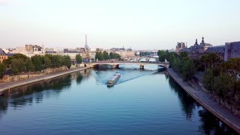 Drone-flying-over-freight-ship-floating-on-calm-Seine-river-in-Moring