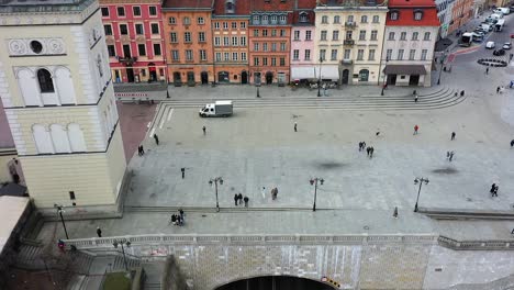 Aerial-view-towards-a-woman-taking-photos-in-Old-town,-Warsaw,-Poland---approaching,-drone-shot